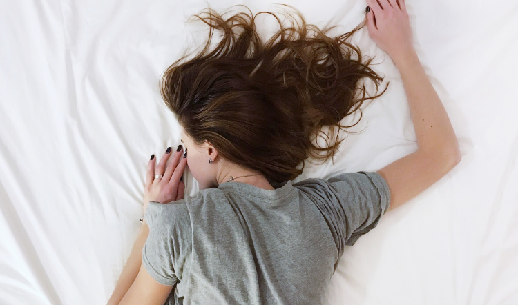 Donna che dorme serenamente nel letto su lenzuola bianche durante il riposo notturno – concetto di sonno e benessere