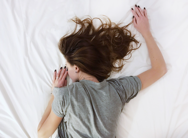 Donna che dorme serenamente nel letto su lenzuola bianche durante il riposo notturno – concetto di sonno e benessere