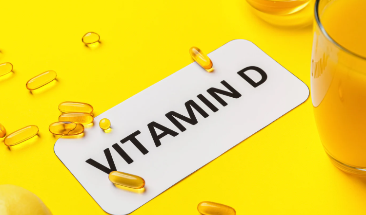 Integratore vitamina D con capsule molli su sfondo giallo e succo d’arancia