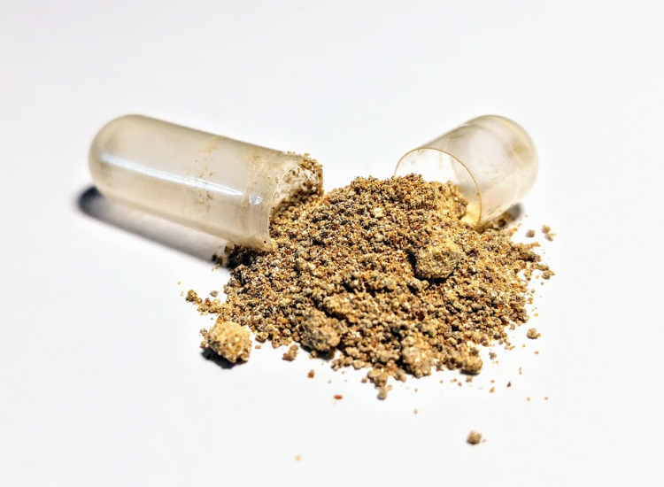 Capsula aperta con polvere di ashwagandha (Withania somnifera) su sfondo bianco